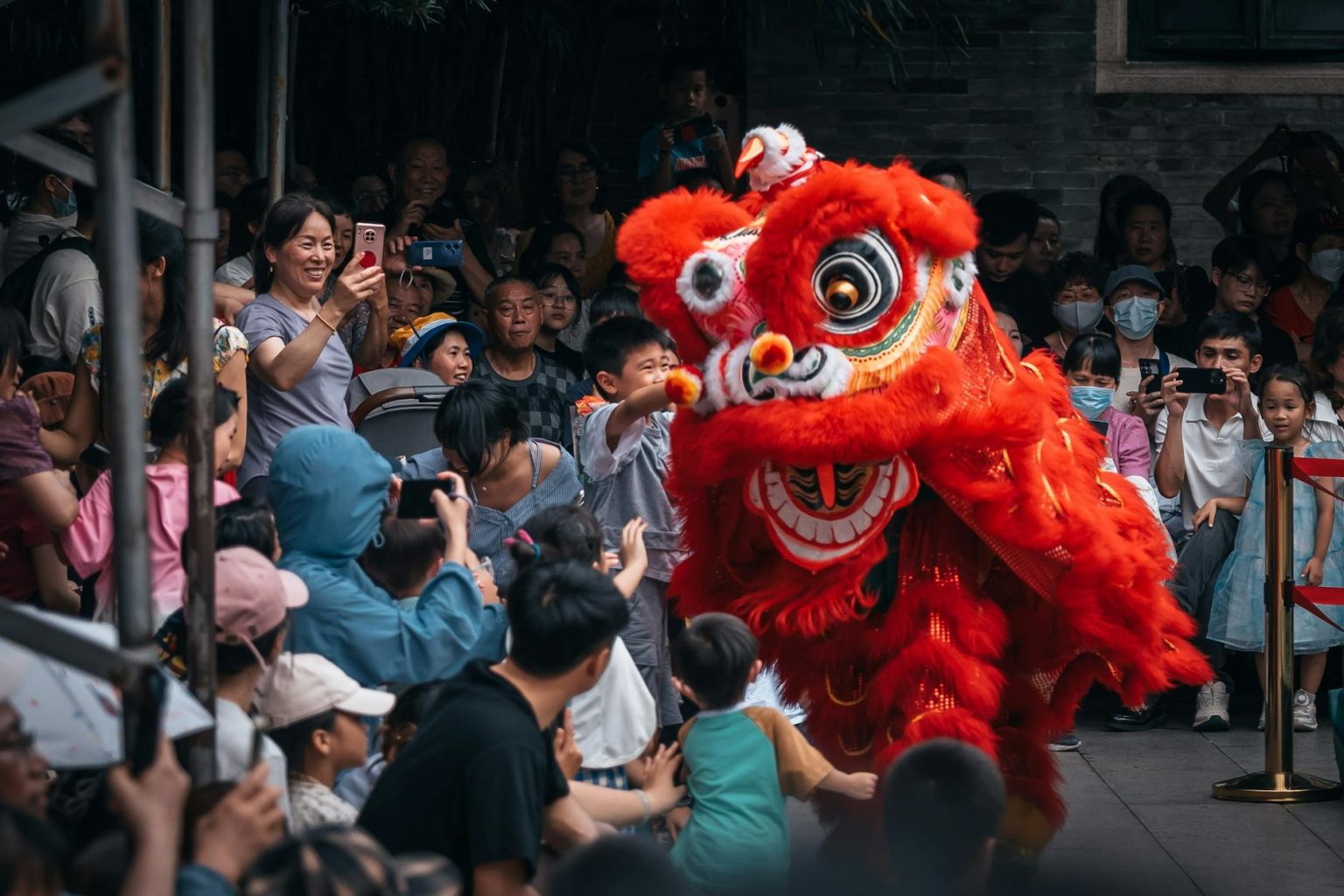 Colorful lion dance performance attracts excited crowd during street celebration.