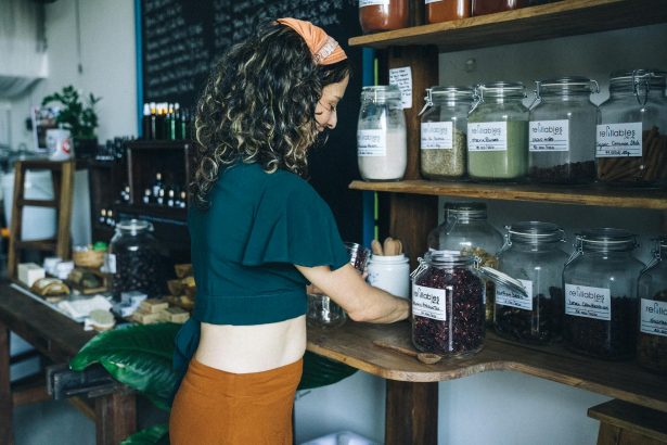 A woman selecting organic items in a refillable jar at an eco-friendly grocery store.