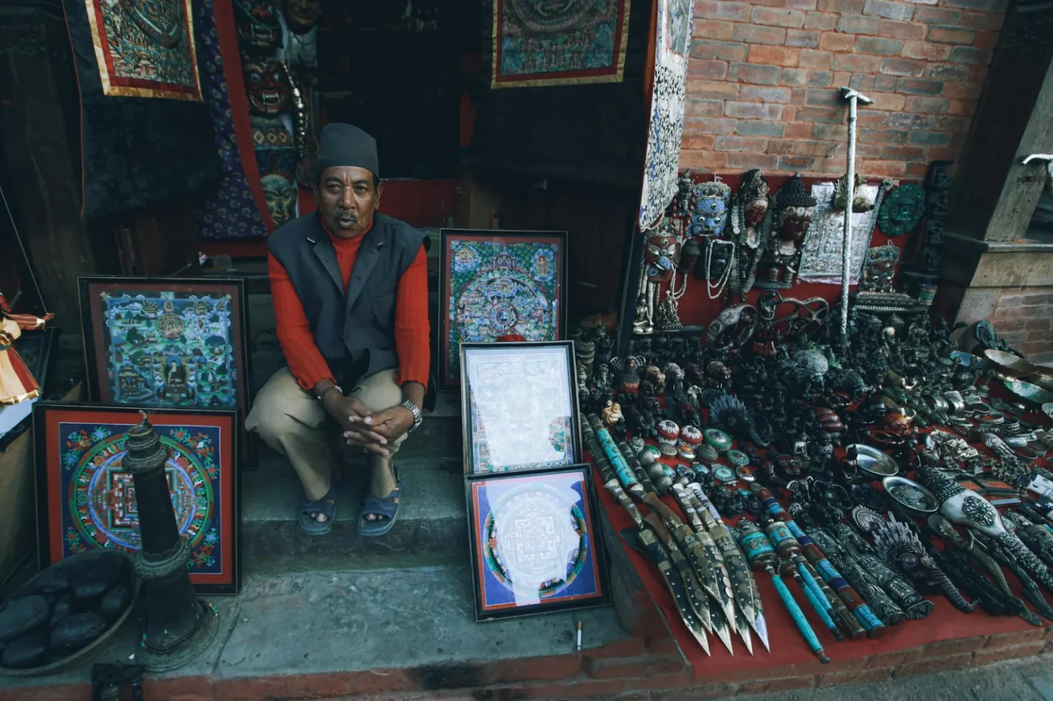Man selling handcrafted items at a traditional street market, surrounded by art and crafts.