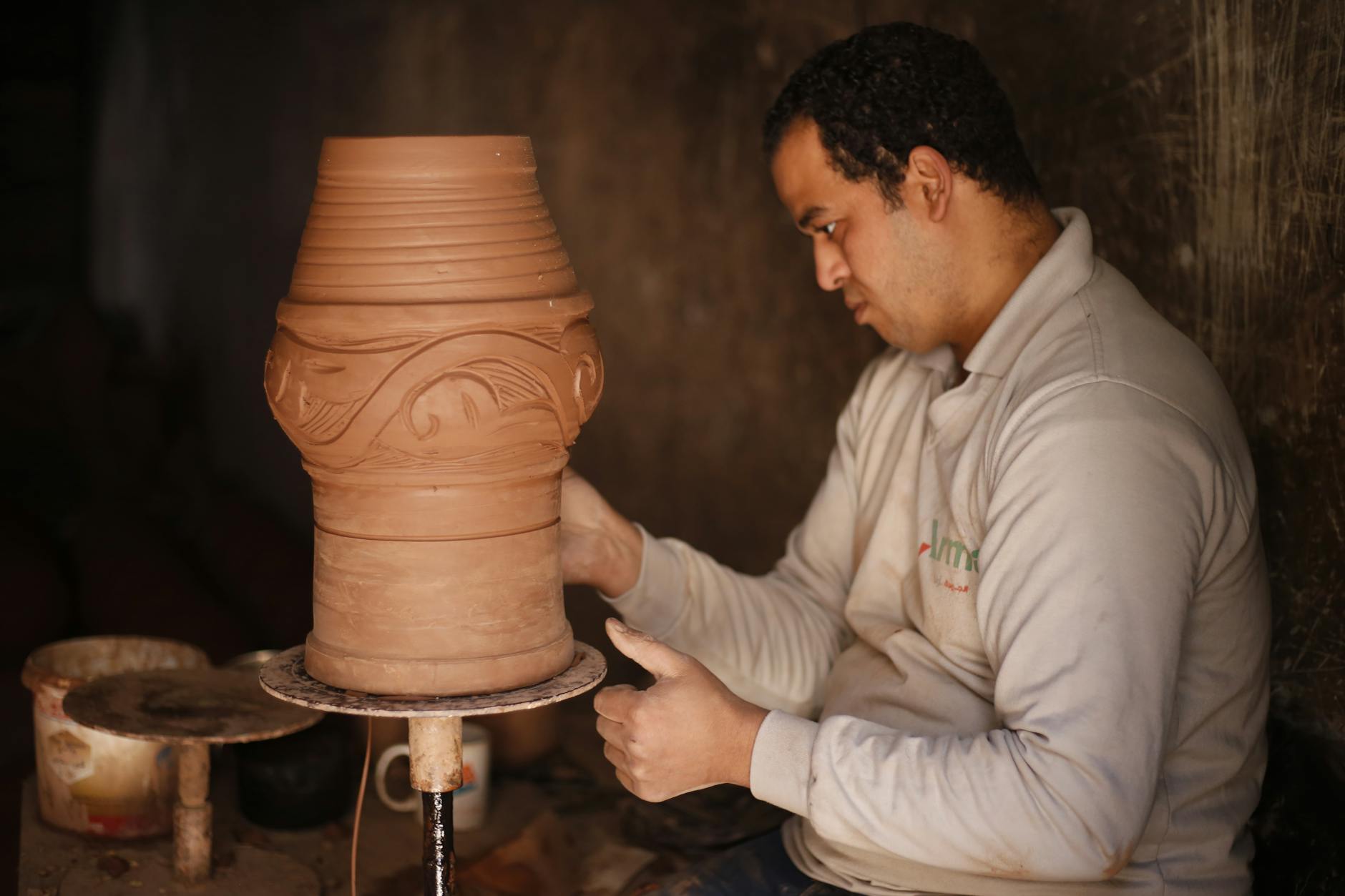 A potter in Cairo skillfully shapes earthenware pottery with attention to detail.