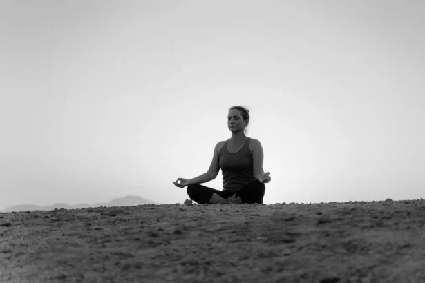 A woman practices meditation on the beach at sunset, embracing tranquility and relaxation.
