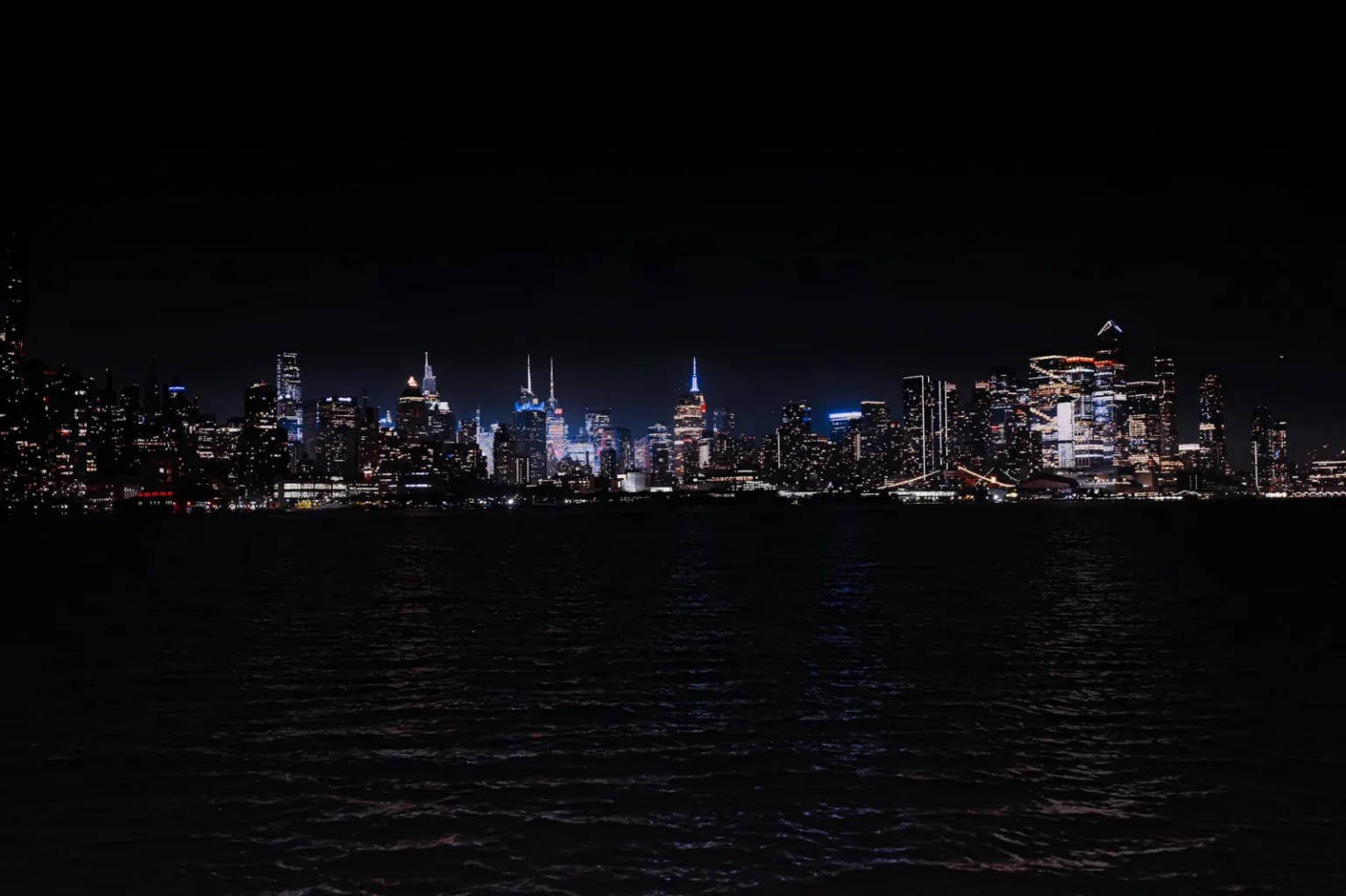 Breathtaking night view of the illuminated New York City skyline across the water.