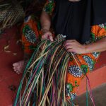 Traditional Indonesian basket weaving by a woman in South Kalimantan, highlighting vibrant cultural heritage.