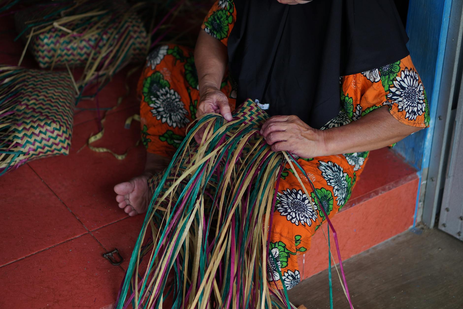 Traditional Indonesian basket weaving by a woman in South Kalimantan, highlighting vibrant cultural heritage.