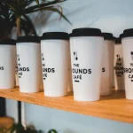 White reusable coffee cups with black lids at The Grounds Café.