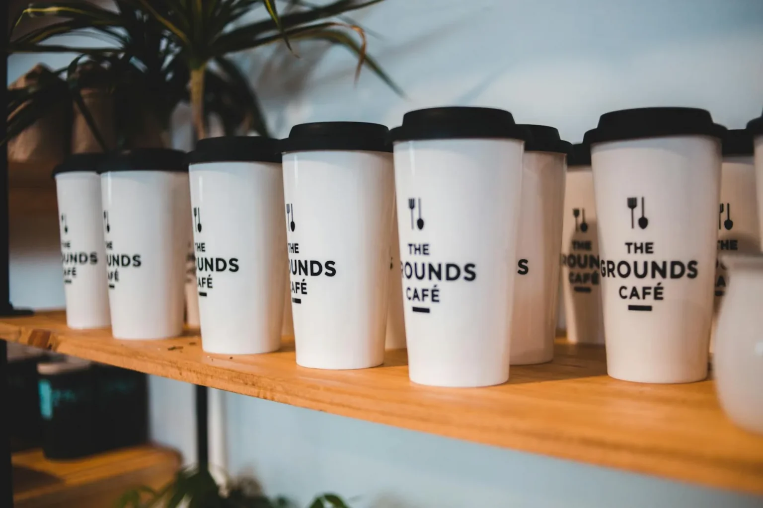 White reusable coffee cups with black lids at The Grounds Café.