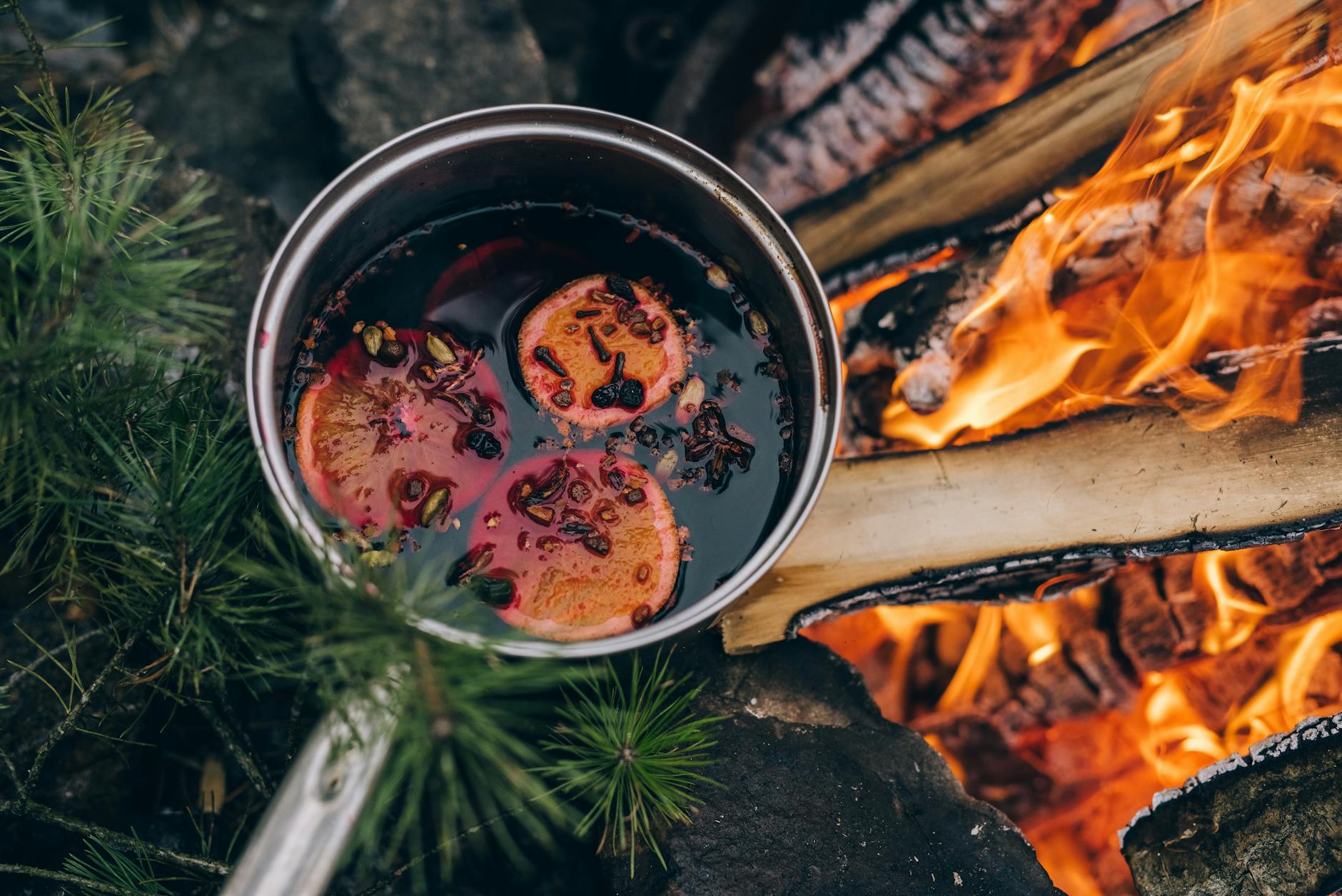 Warm mulled wine with spices simmering in a pot over an open fire. Perfect for cozy winter evenings.