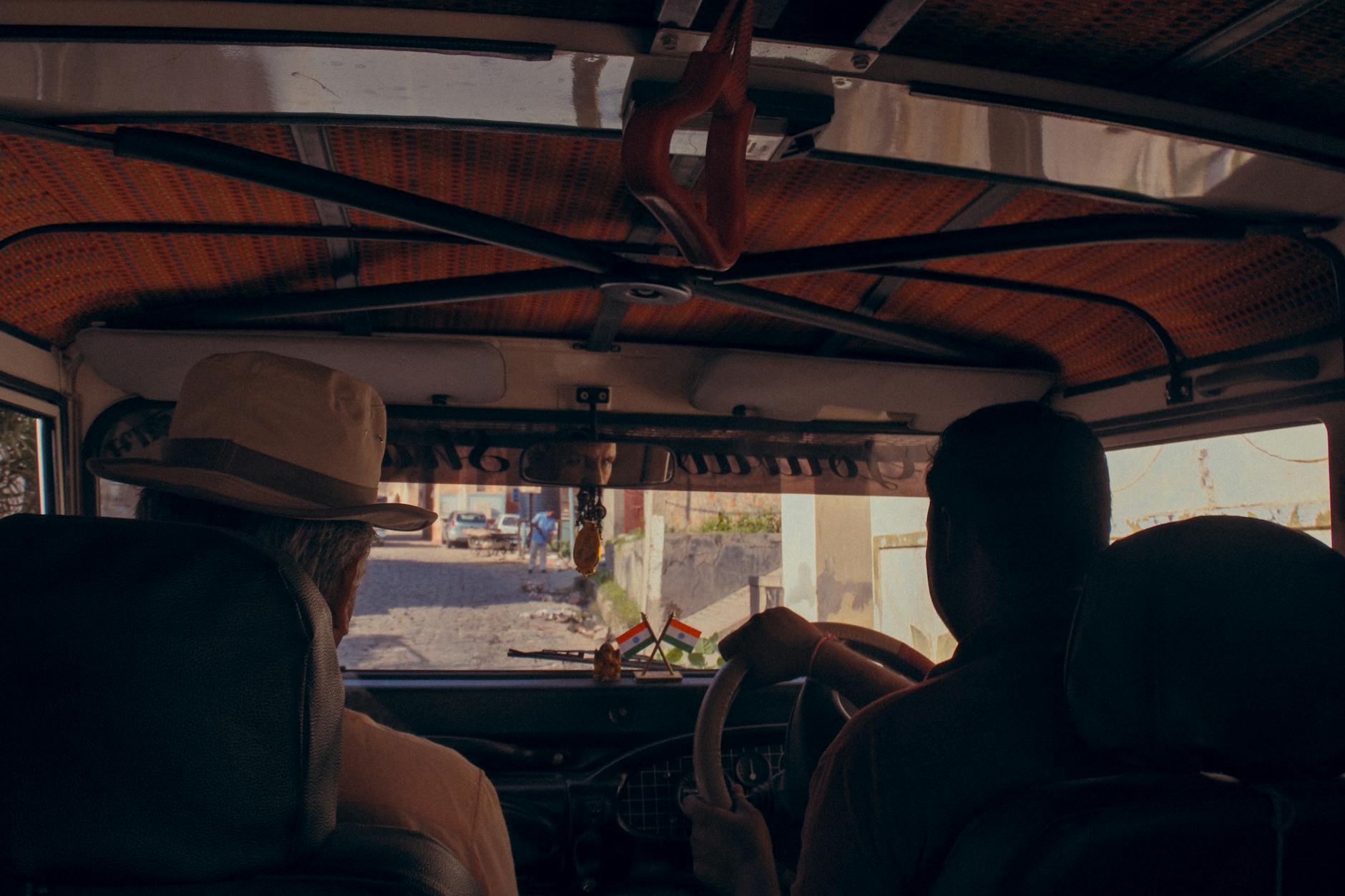 Interior of a vehicle driving through a rustic road in India, capturing cultural essence.