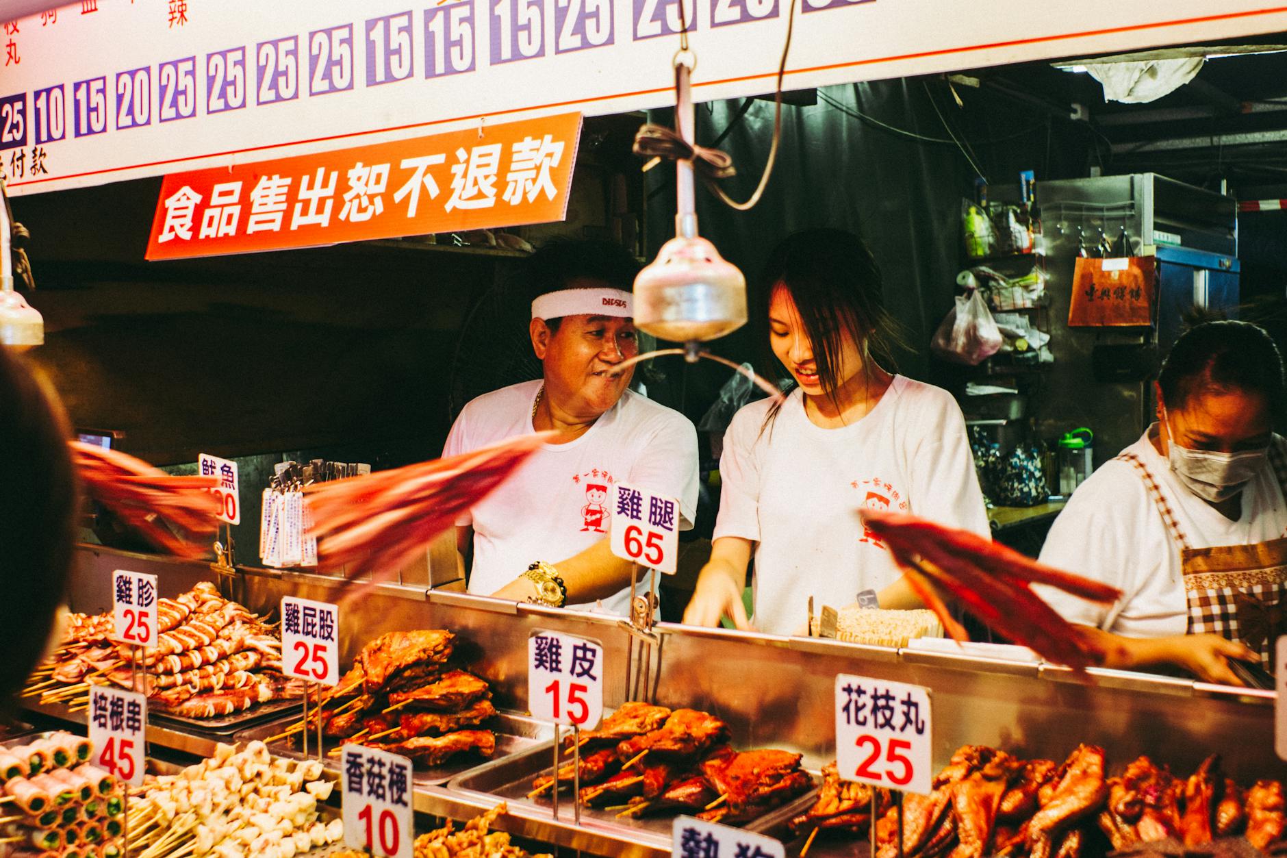 Vibrant scene at a bustling Taiwanese night market food stall with vendors.