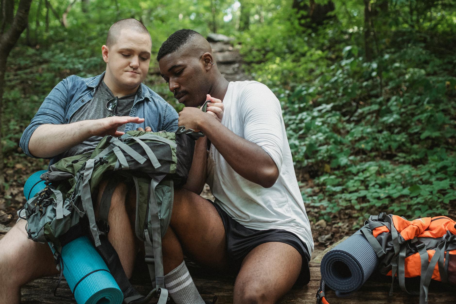 Two friends sitting in the forest sharing a peaceful hiking break amidst greenery.