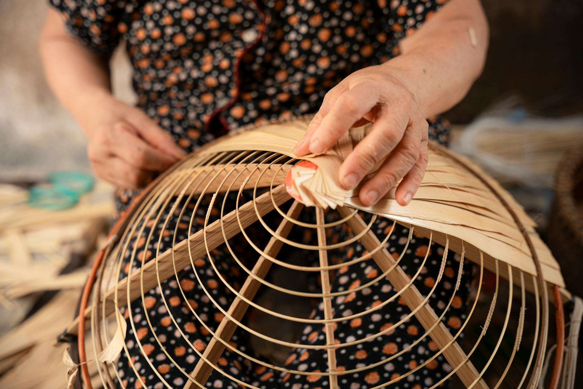 Close-up of a person weaving a traditional Vietnamese bamboo basket by hand.