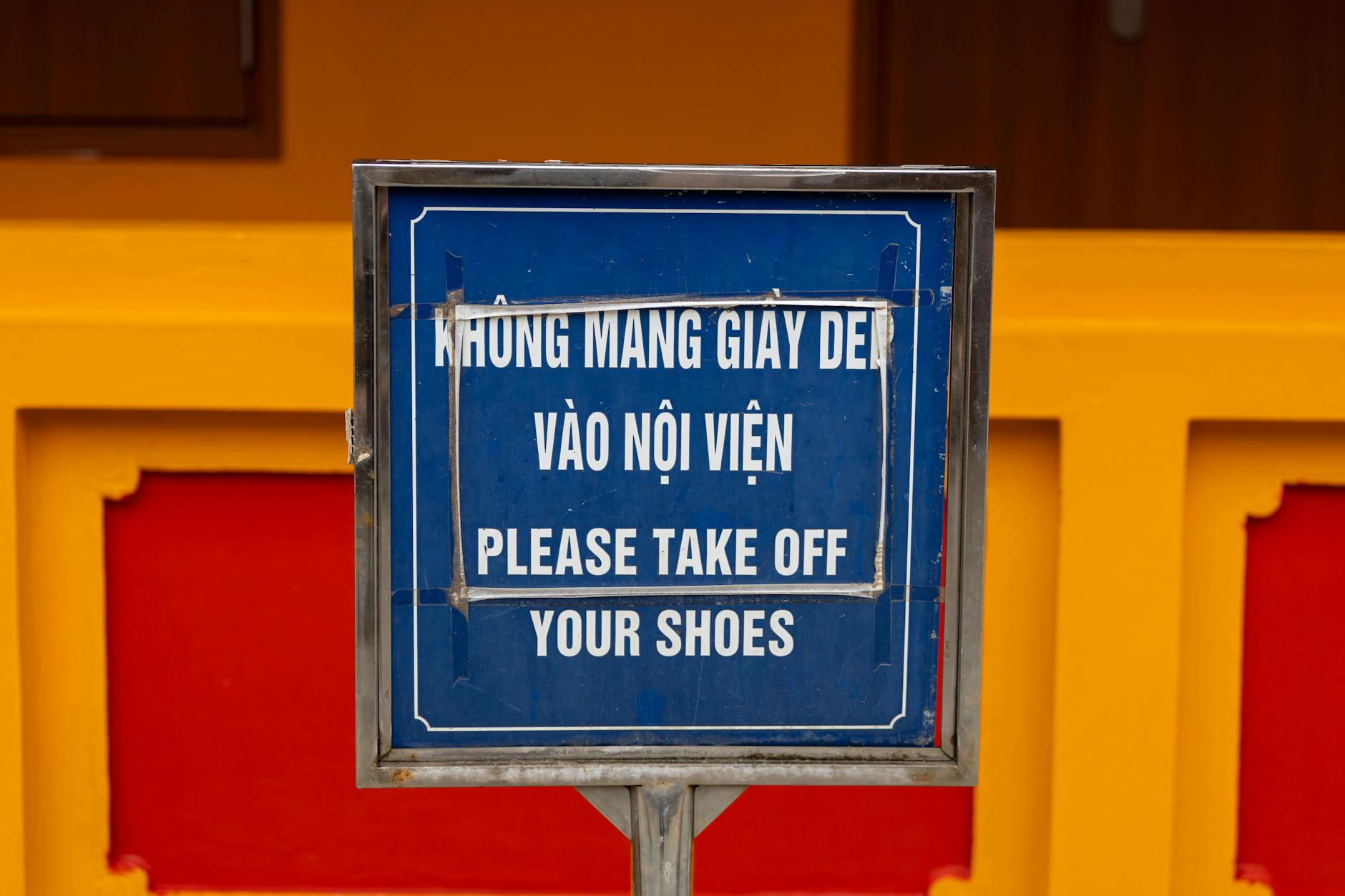 Close-up of bilingual sign in Hà Nội, Việt Nam, advising to remove shoes before entering.