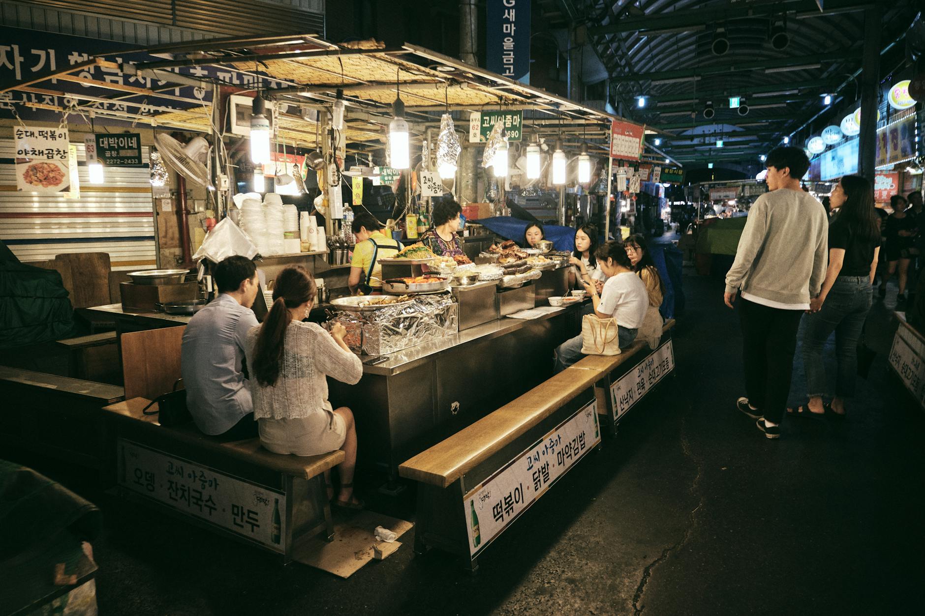 Night market in Seoul bustling with people enjoying street food. A vibrant and lively atmosphere.