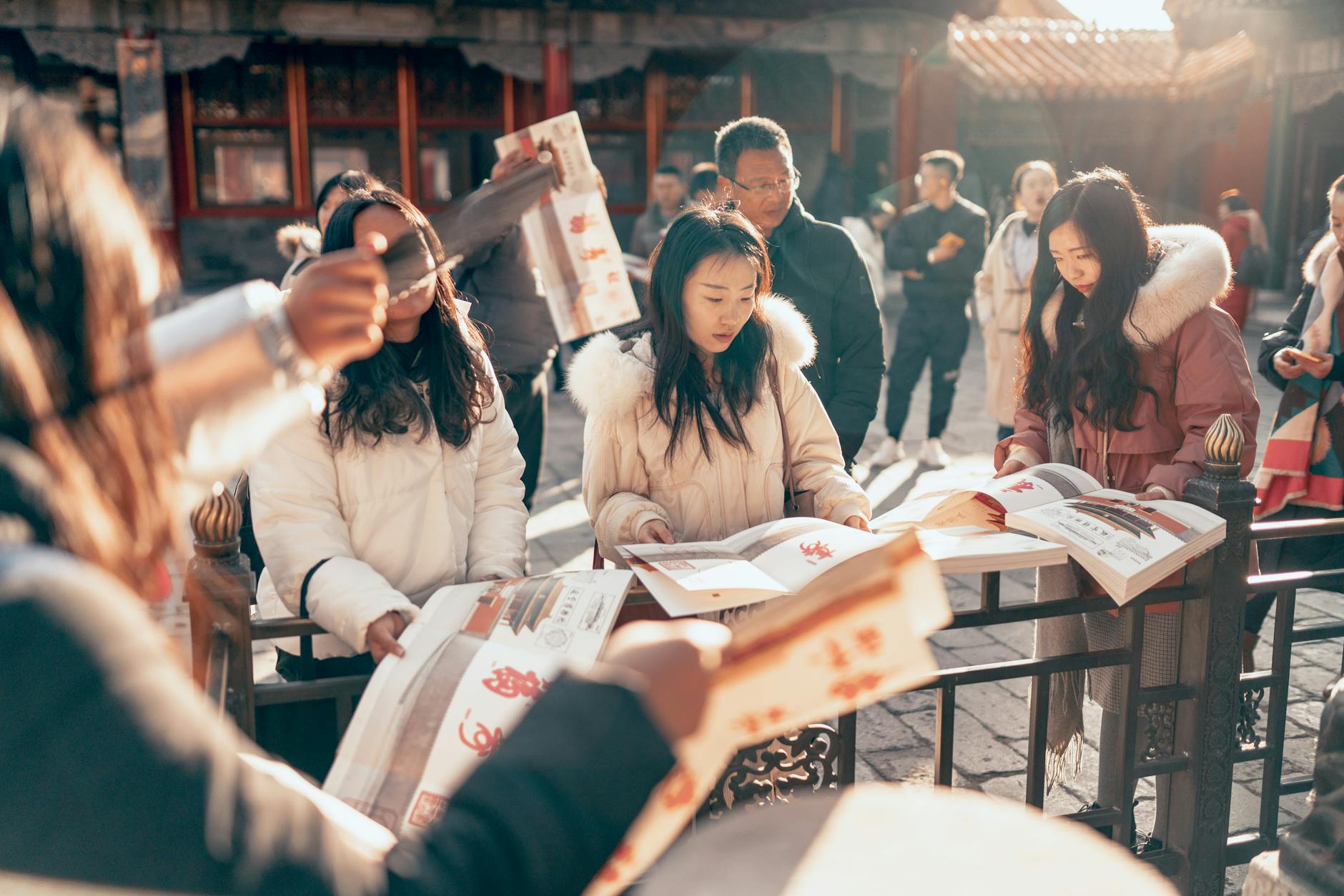 Group of Asian tourists reading guidebooks while exploring a historical landmark during winter.