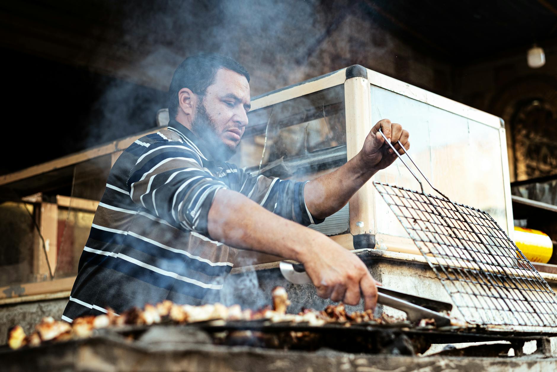 A street vendor grills meat outdoors at a bustling market stall in Egypt, showcasing local culinary culture.