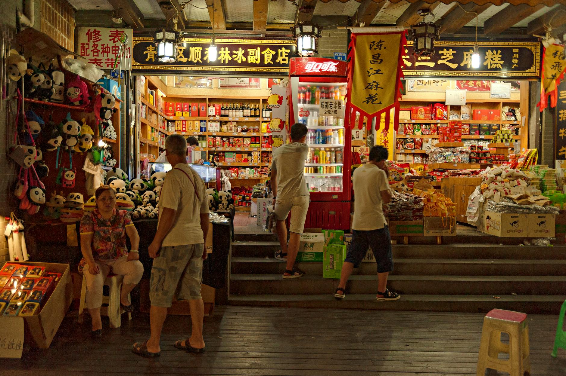 Busy night market with people and colorful products, showcasing Asian culture.