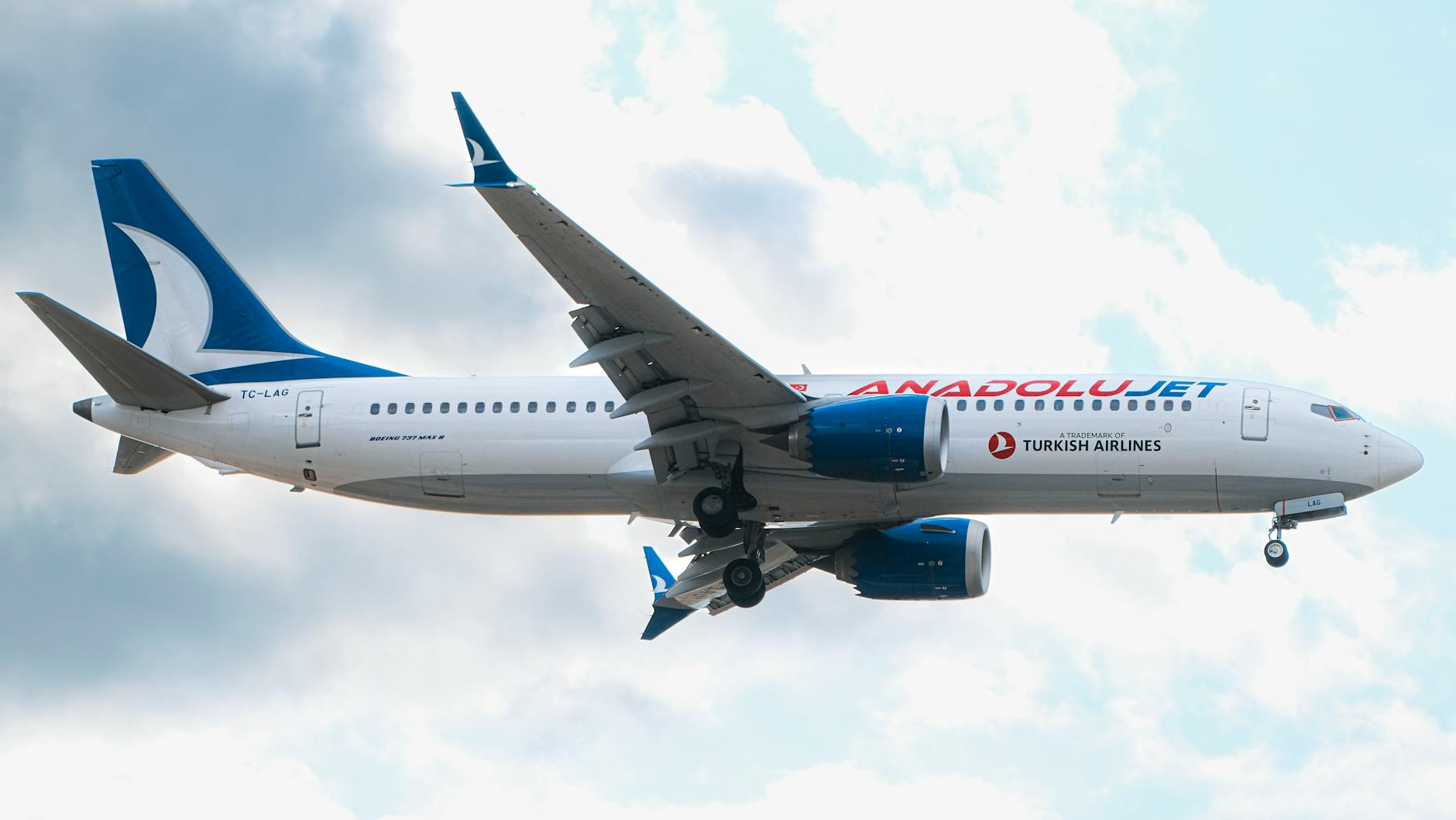 A Boeing 737 plane from AnadoluJet captured mid-air against a cloudy sky.