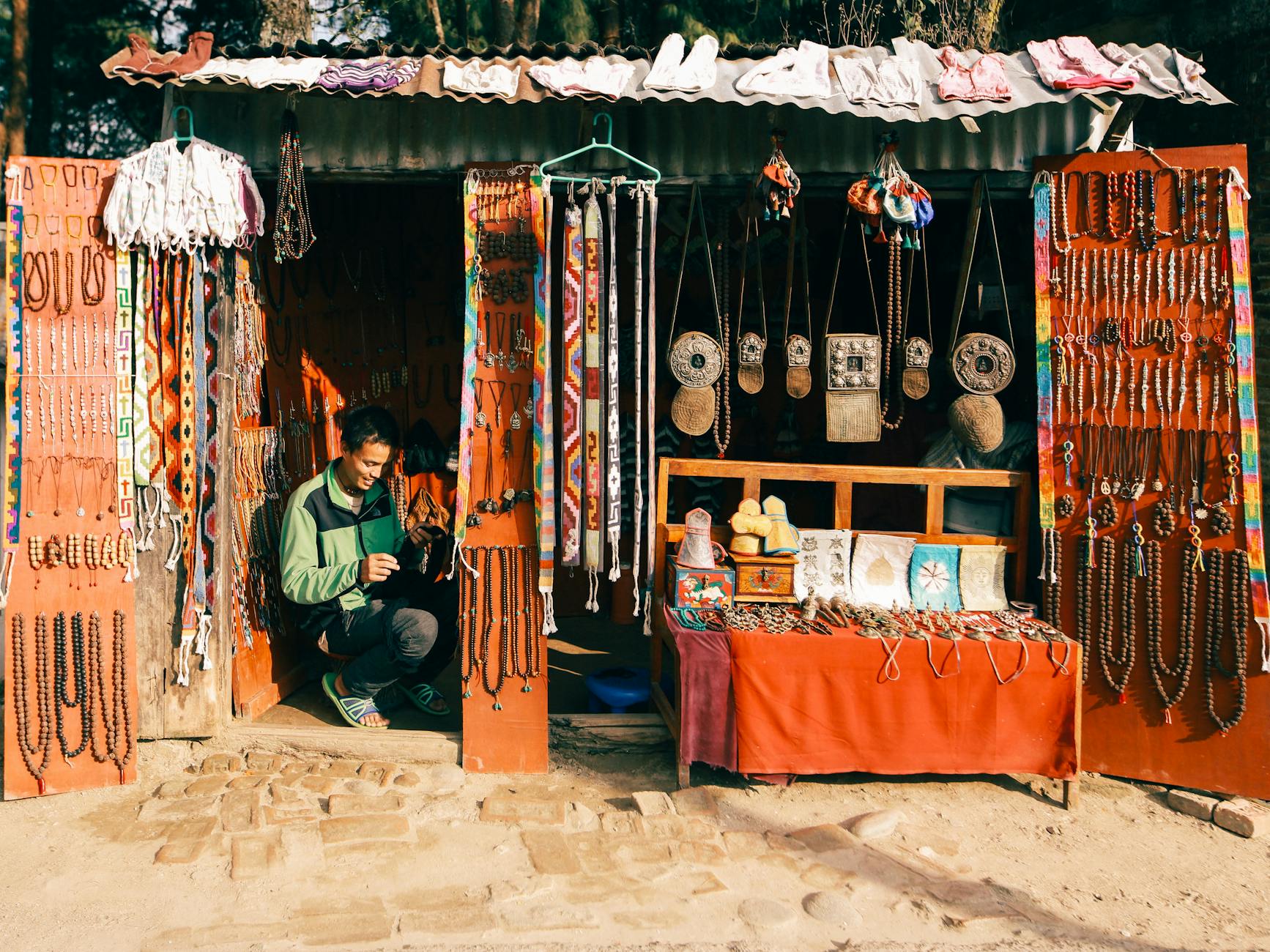 A vibrant street market stall selling traditional jewelry with a smiling vendor.