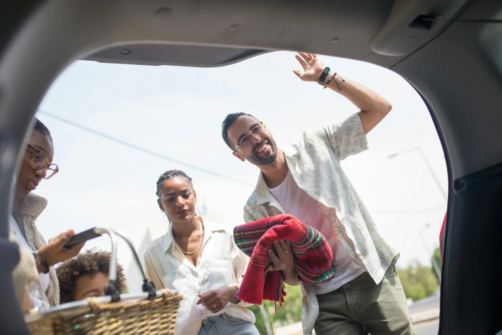 A family enjoys a picnic day outing, loading a car with love and joy on a sunny day.