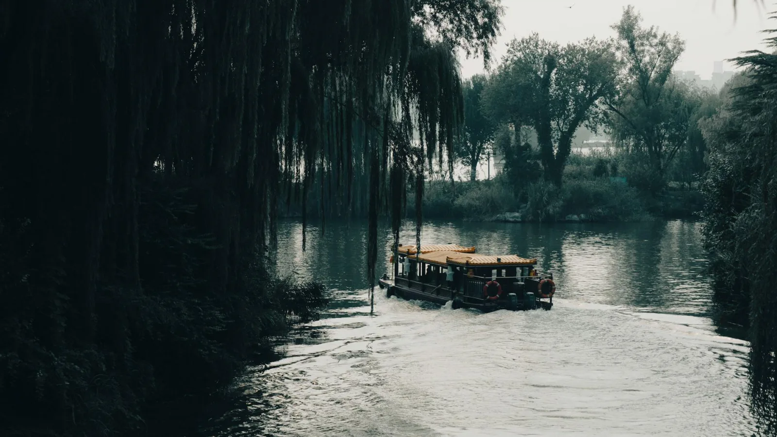 Tranquil scene of a boat sailing through a misty jungle river, evoking adventure.