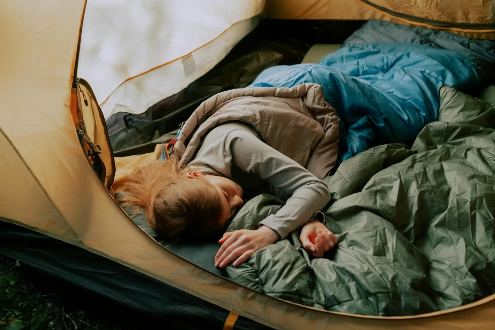 A serene scene of a woman sleeping comfortably in a tent during a camping trip, surrounded by nature.