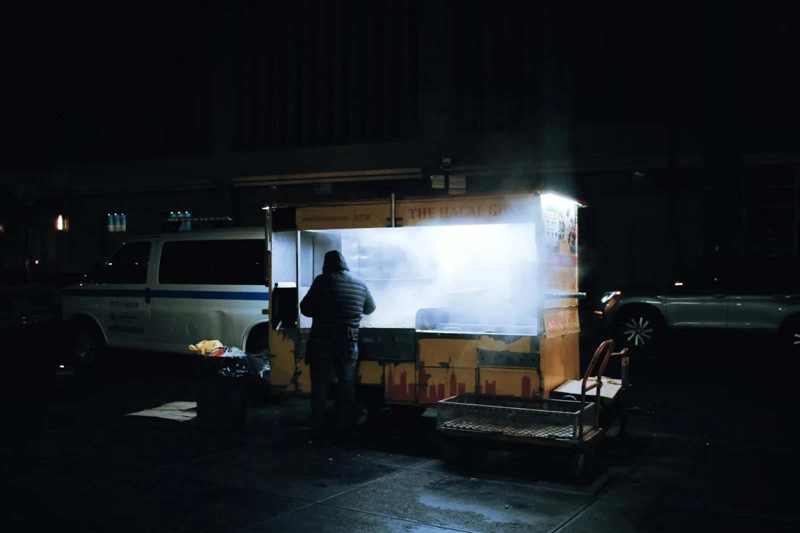 A street vendor prepares food at a night market with illuminated smoke.