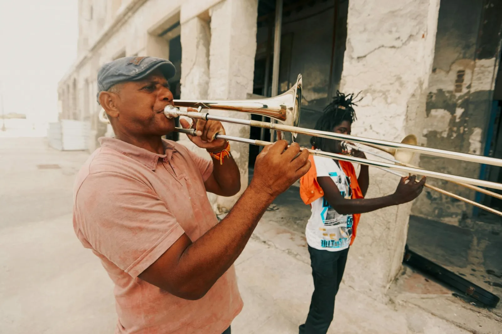 Two men playing trombones on a city street, capturing the essence of urban street music.