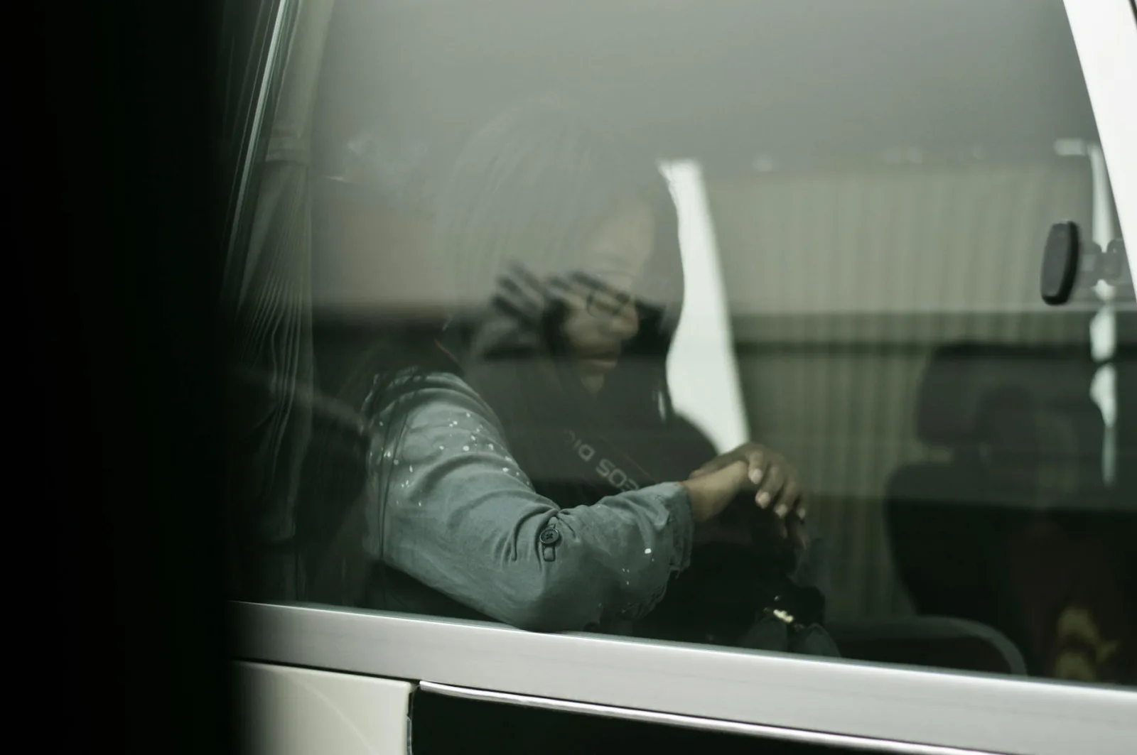 A woman waits in a car, reflecting through the window in Cairo, Egypt.