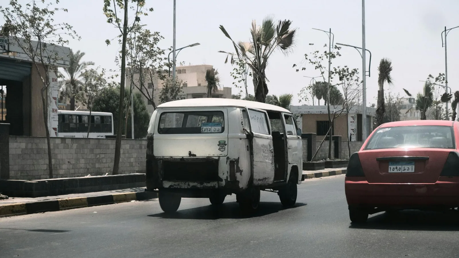 A scene of urban life featuring a vintage van and red car on a street in Cairo, Egypt.
