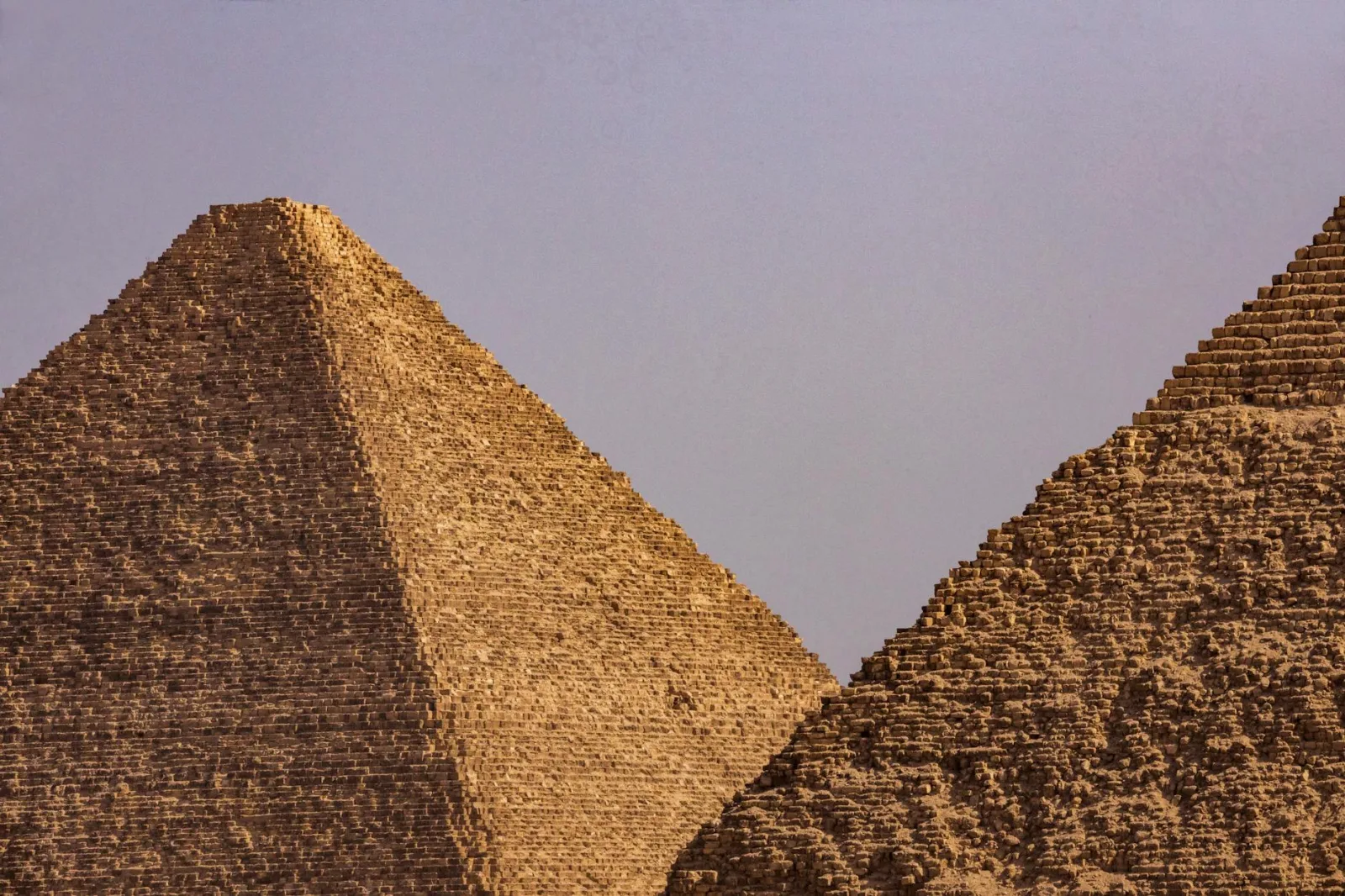 A close-up view of two iconic Egyptian pyramids under a clear blue sky.