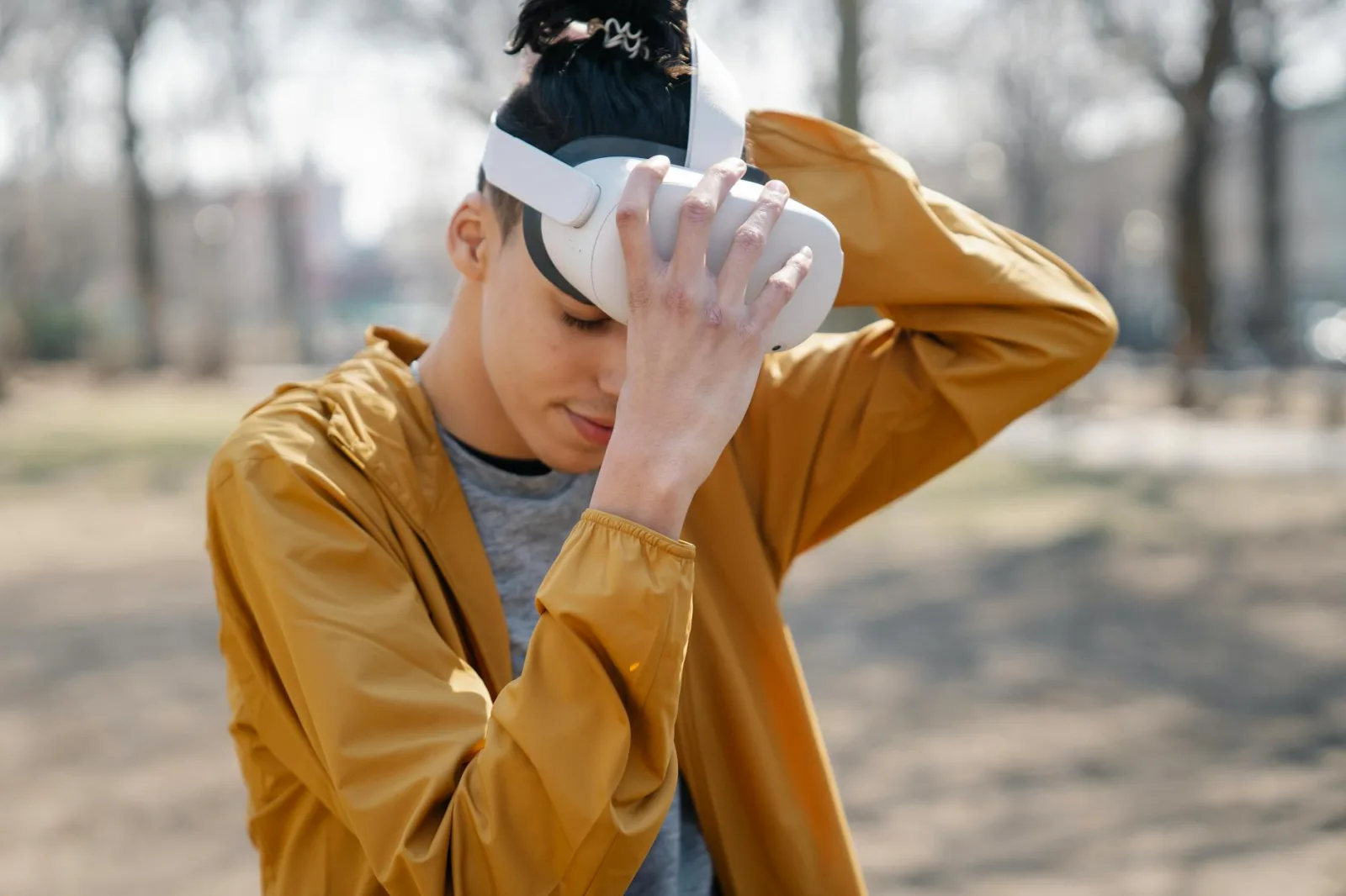 Man with closed eyes putting on VR device against blurred background of autumn city park in daytime