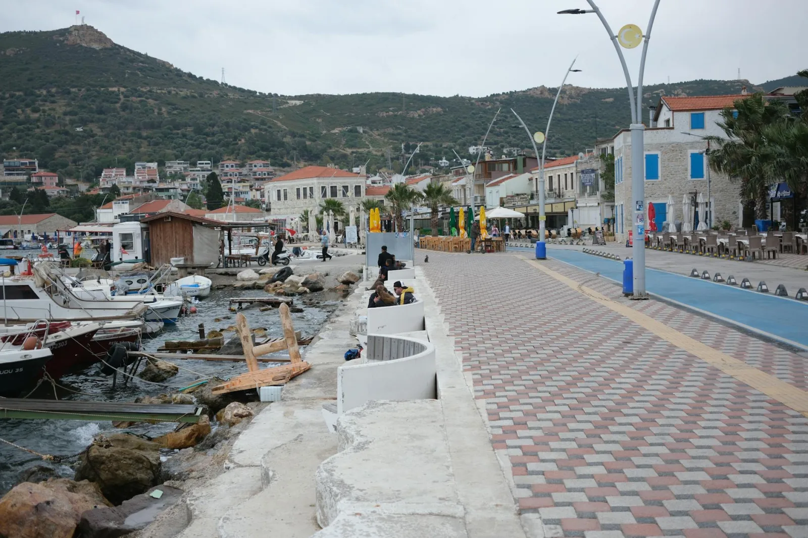 Explore the scenic Foça harbor with boats and promenade in Izmir, Türkiye.