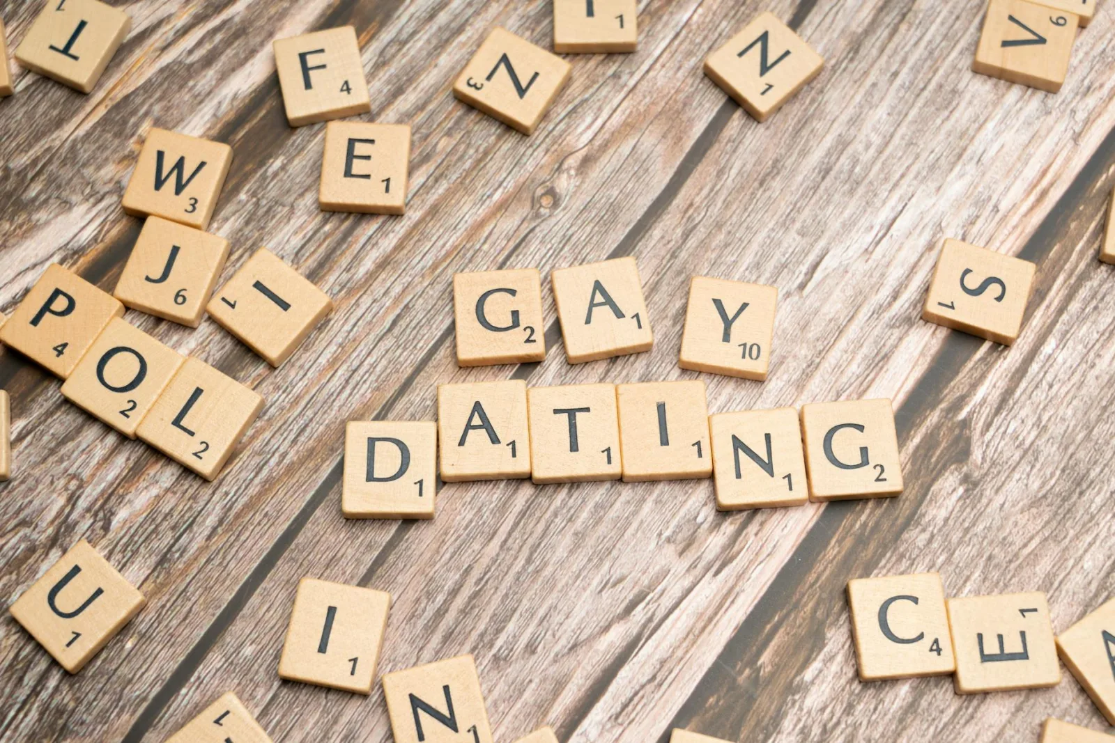 Scrabble tiles spelling 'Gay Dating' on a rustic wooden background, representing LGBTQ themes.