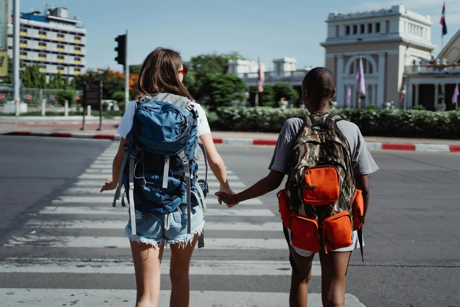 Two backpackers crossing a city street, showcasing friendship and travel excitement.