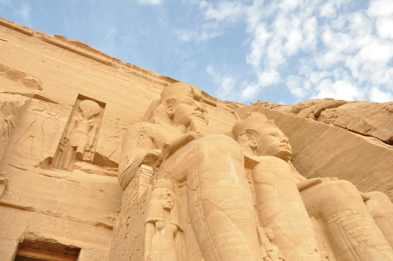 Ancient sandstone statues of pharaohs at Abu Simbel, Egypt, under a clear blue sky.