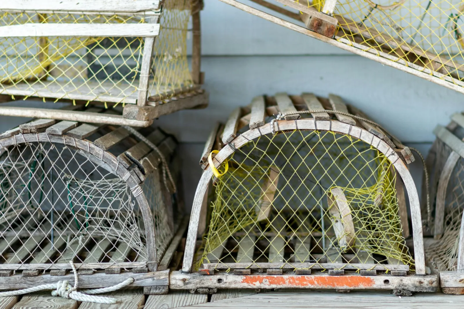 Stacked wooden crab traps with yellow netting, highlighting traditional fishing equipment.