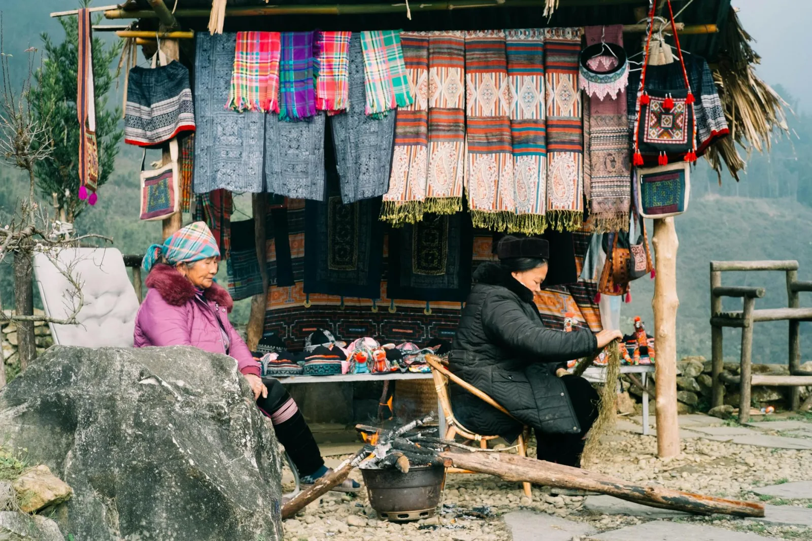Colorful handmade textiles displayed at an outdoor market with local vendors in traditional attire.