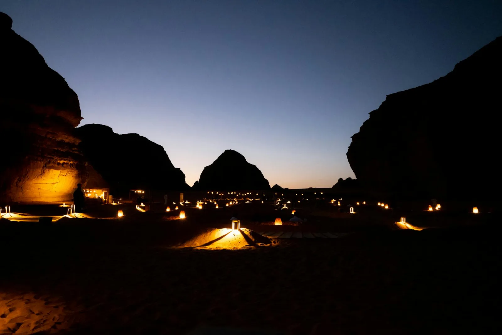 Experience the magical desert landscape of AlUla at dusk, beautifully lit by lanterns.