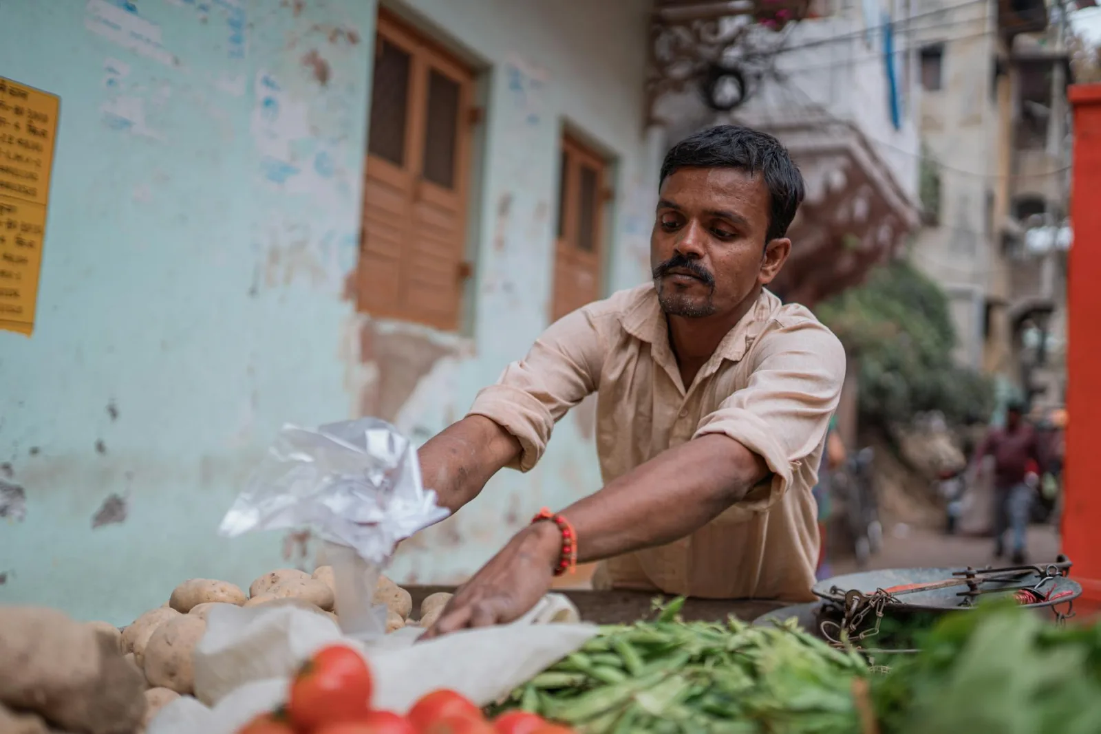 A vendor arranging fresh vegetables at a street market in Varanasi, India.
