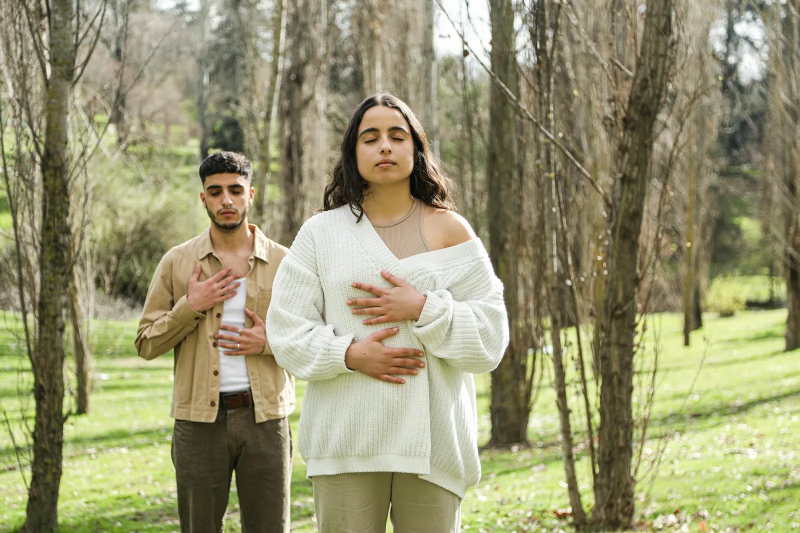 Two people meditating outdoors with eyes closed, enveloped in nature's tranquility.