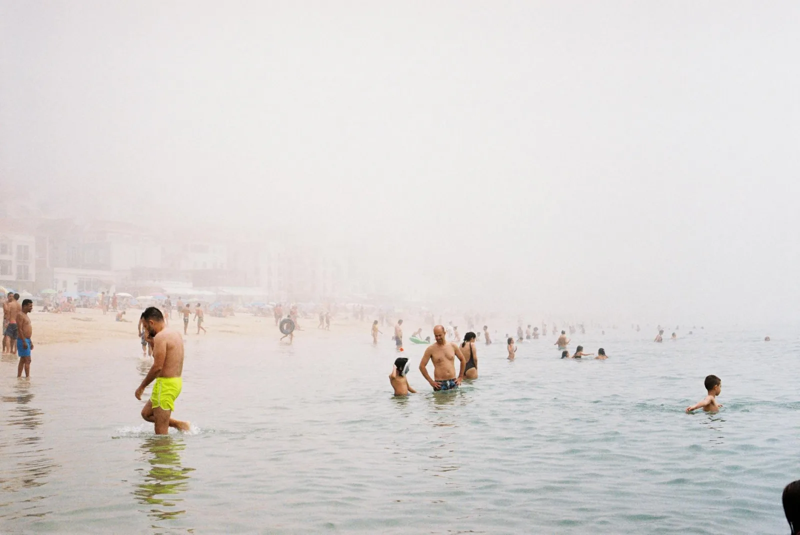 People enjoying a foggy day at the beach, swimming and relaxing.
