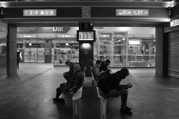 Black and white photo of travelers sitting in an airport terminal, waiting.