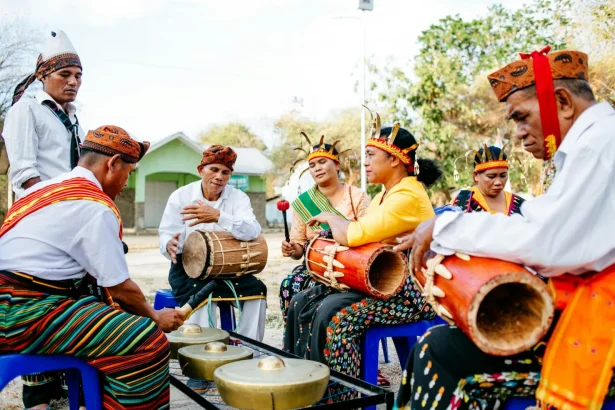 A group of musicians in traditional attire play instruments at a festival in Indonesia.