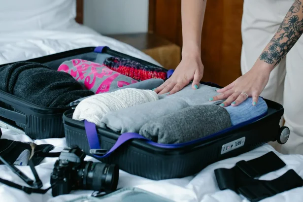 Hands packing rolled clothes into a suitcase, highlighting efficient travel organization.