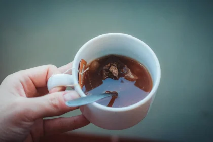 Elevated shot of a teacup with a tea bag and spoon in hand.