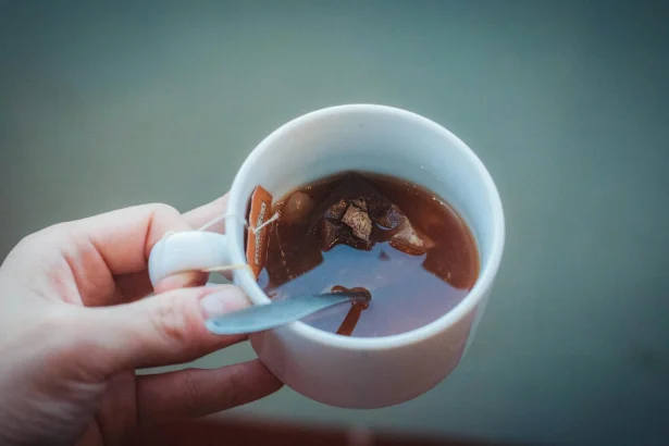 Elevated shot of a teacup with a tea bag and spoon in hand.