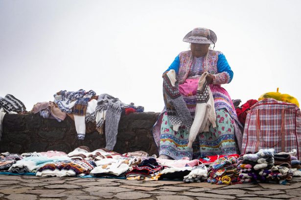 Indigenous woman selling colorful handmade textiles in Arequipa, Peru.