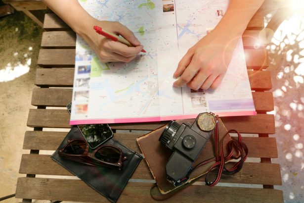 A person planning a journey using a map and vintage camera, evoking travel and exploration.