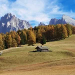 Idyllic autumn landscape in Trentino-Alto Adige with wooden bungalows and mountain views.
