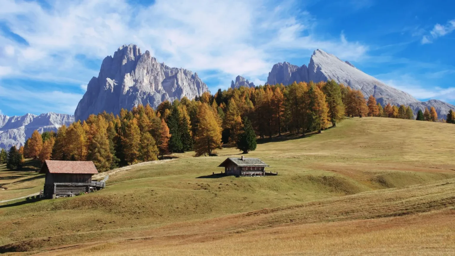 Idyllic autumn landscape in Trentino-Alto Adige with wooden bungalows and mountain views.
